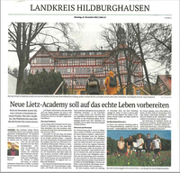 A newspaper shows a large building in the background and people in the foreground.
