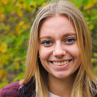 Eine junge Frau mit blonden Haaren lächelt freundlich in die Kamera.