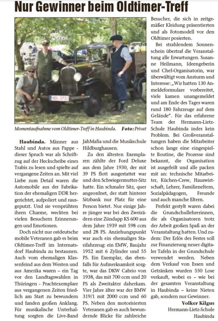 Zeitungsausschnitt über ein Oldtimertreffen mit einem alten Auto im Vordergrund.