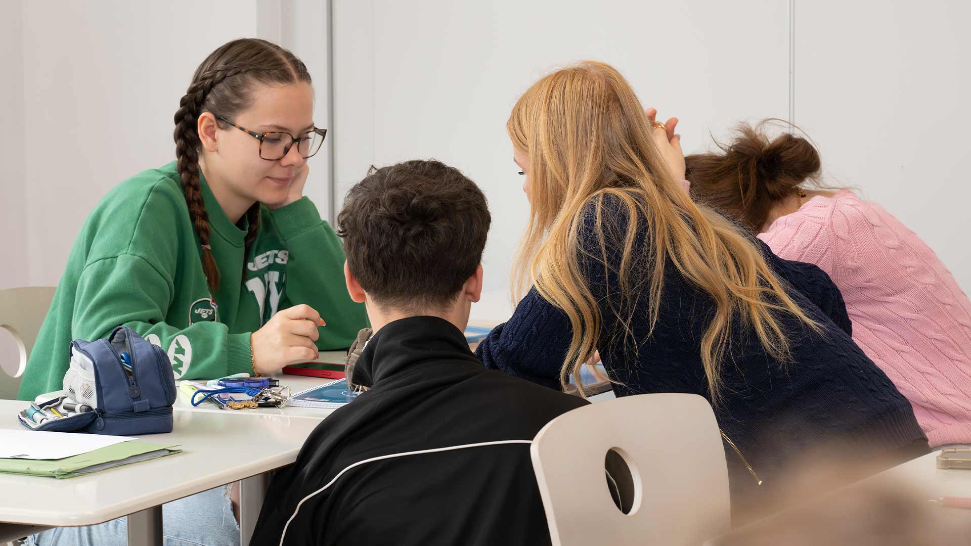 Vier Personen sitzen an einem Tisch und arbeiten gemeinsam an einer Aufgabe.