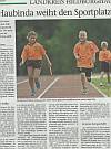 Two smiling children in orange shirts are running on a track.