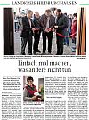 A group of people are cutting a red ribbon at a ceremony.