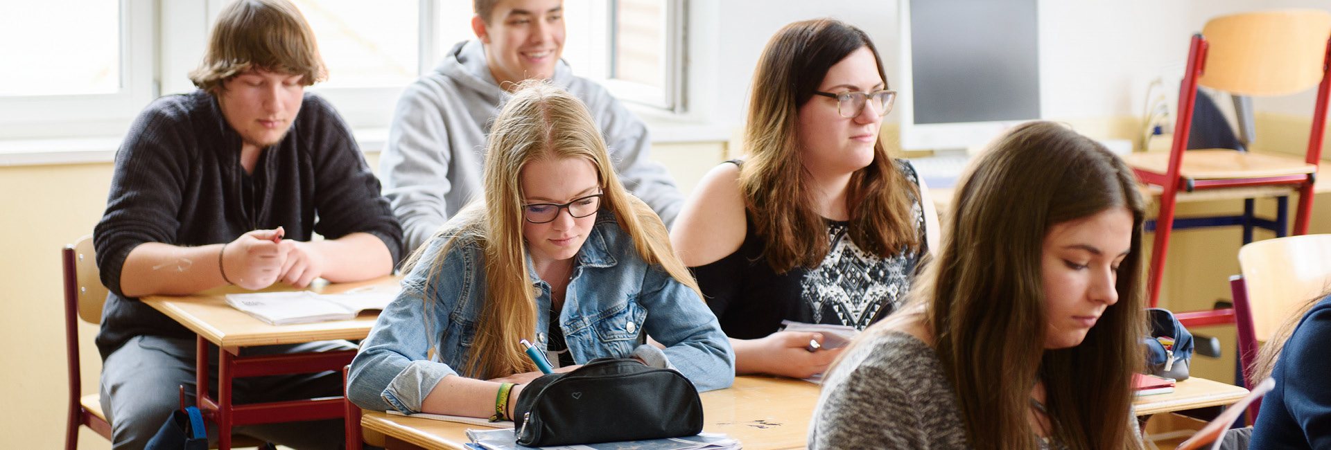 Eine Gruppe junger Menschen lernt konzentriert in einem Klassenzimmer.