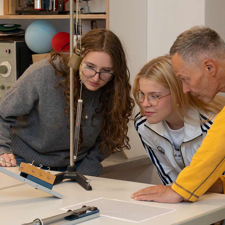 Drei Personen betrachten ein wissenschaftliches Experiment voller Interesse.
