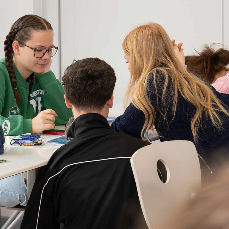 Eine Gruppe junger Menschen arbeitet konzentriert gemeinsam an einem Tisch.