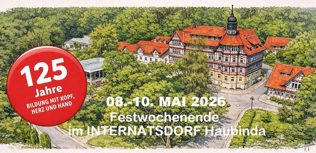 Ein großes historisches Gebäude mit rotem Dach liegt umgeben von grünem Wald
