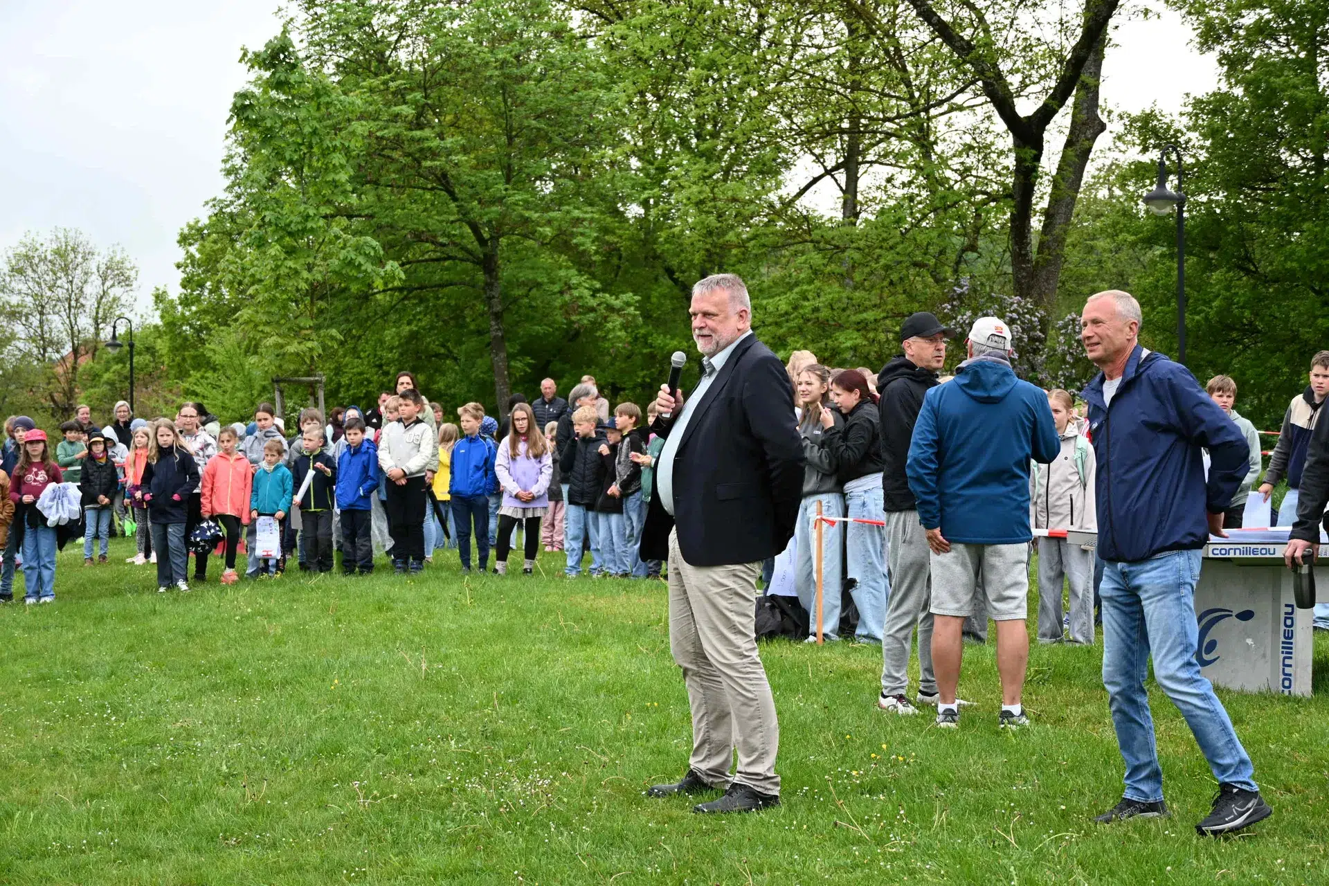 Ein Mann im Anzug wirkt nachdenklich vor einer großen bunt gekleideten Menschenmenge