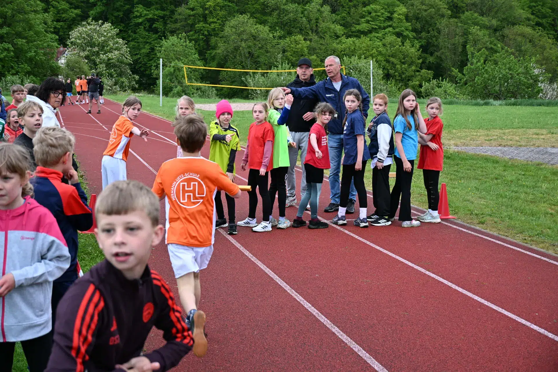 Mehrere Kinder stehen in bunter Sportkleidung lachend an einer Laufbahn