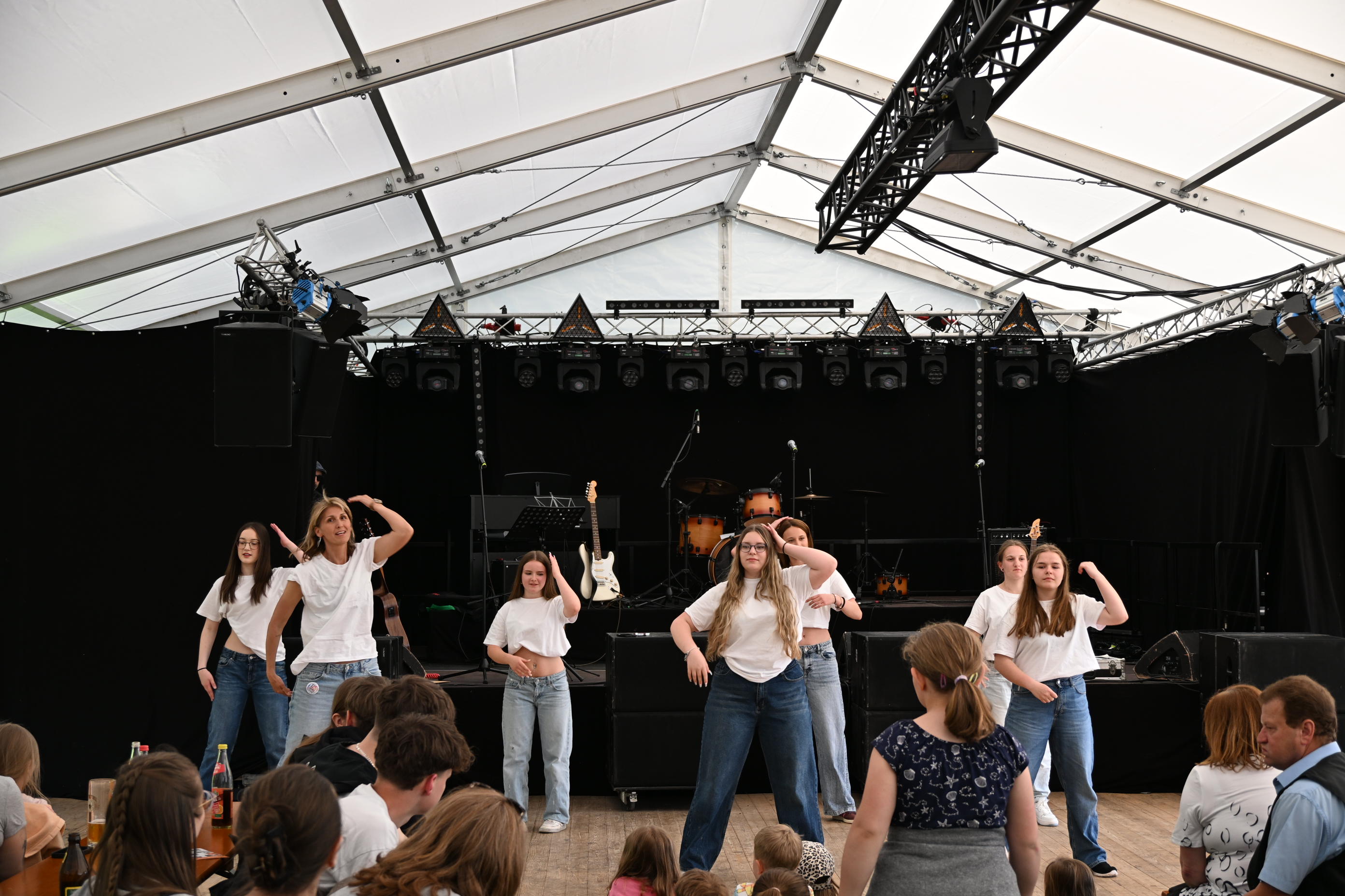 A Gruppe junger Frauen tanzt im weißen Shirt und blauen Jeans auf der Bühne