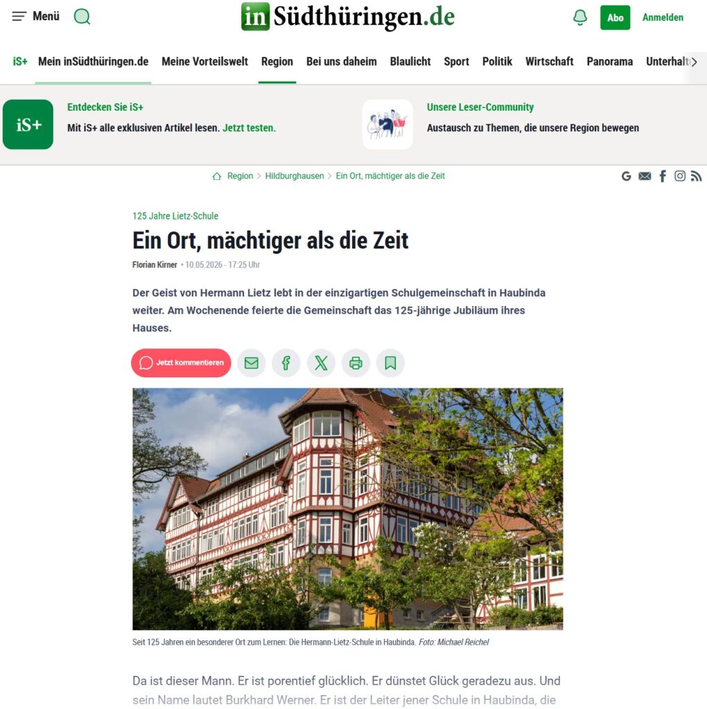 Mehrstöckiges Fachwerkhaus mit roten und weißen Akzenten und grünen Bäumen