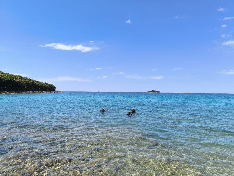 Zwei Schwimmer im klaren türkisblauen Meer mit Inseln am Horizont