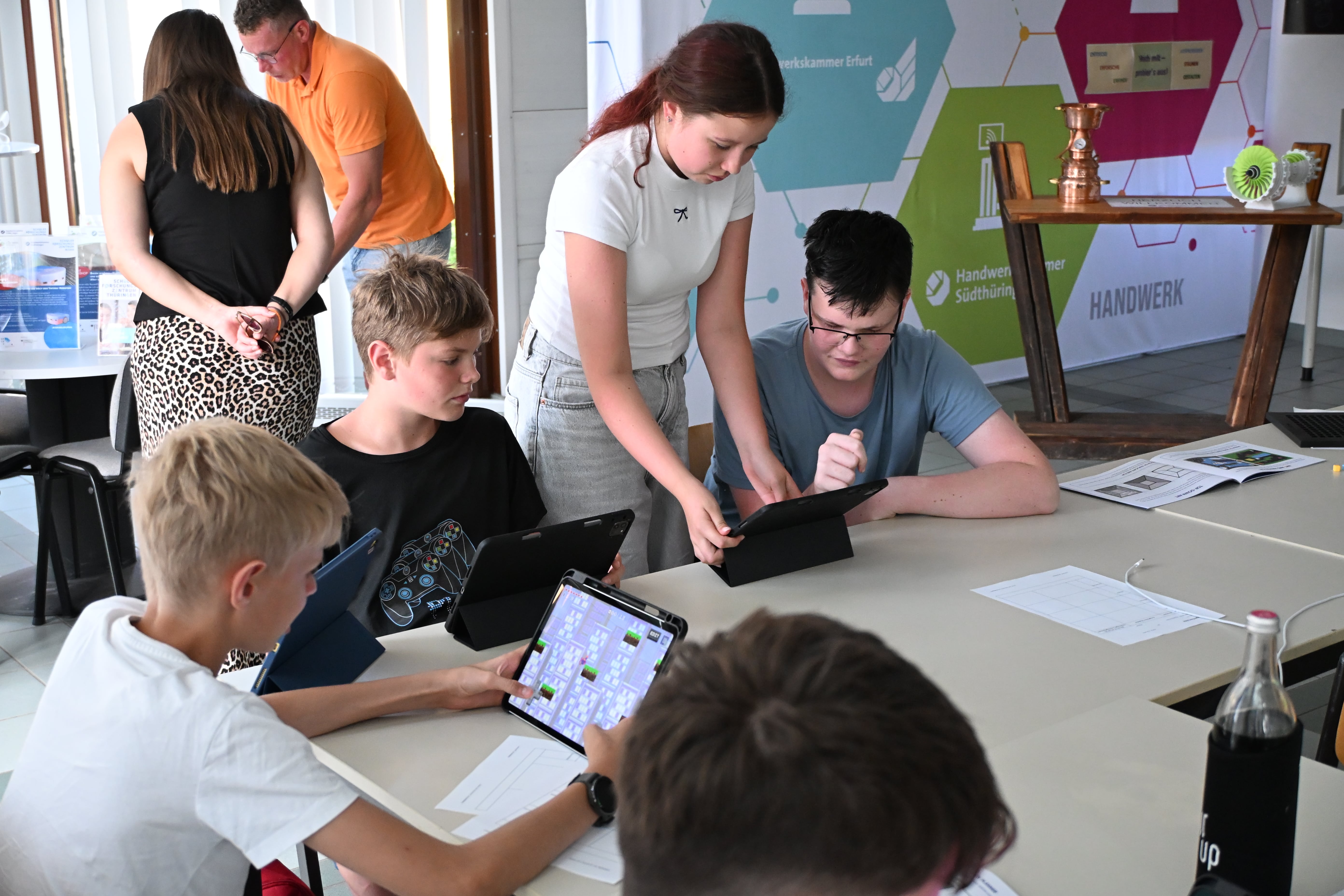 Fokussierte Jugendliche arbeiten an Tablets am Tisch in hellem Raum