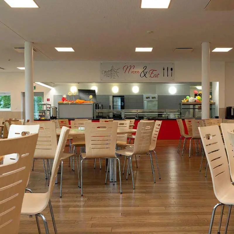 Leere Cafeteria mit neutraler Stimmung, weiBe Stuehle, roter Akzent, Menu Eat Schild