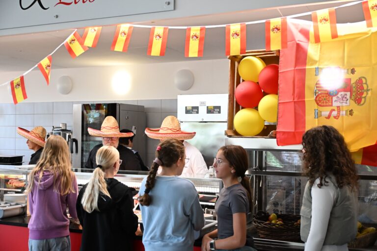 Kuechenpersonal mit Sombreros serviert Schuelern an spanisch geschmueckter Theke