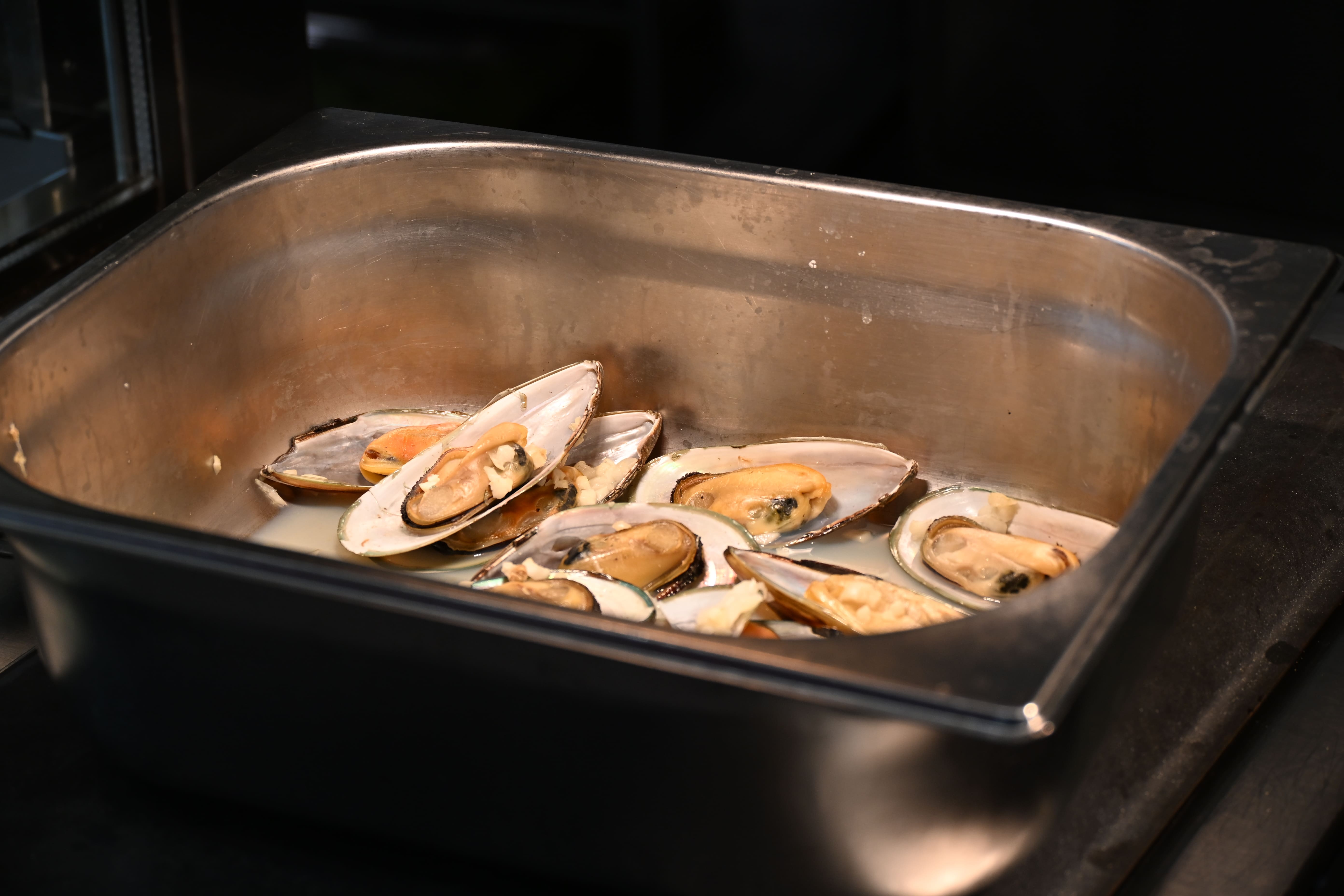 Gedaempfte Muscheln mit Knoblauch in einem Edelstahlbehaelter im Buffet