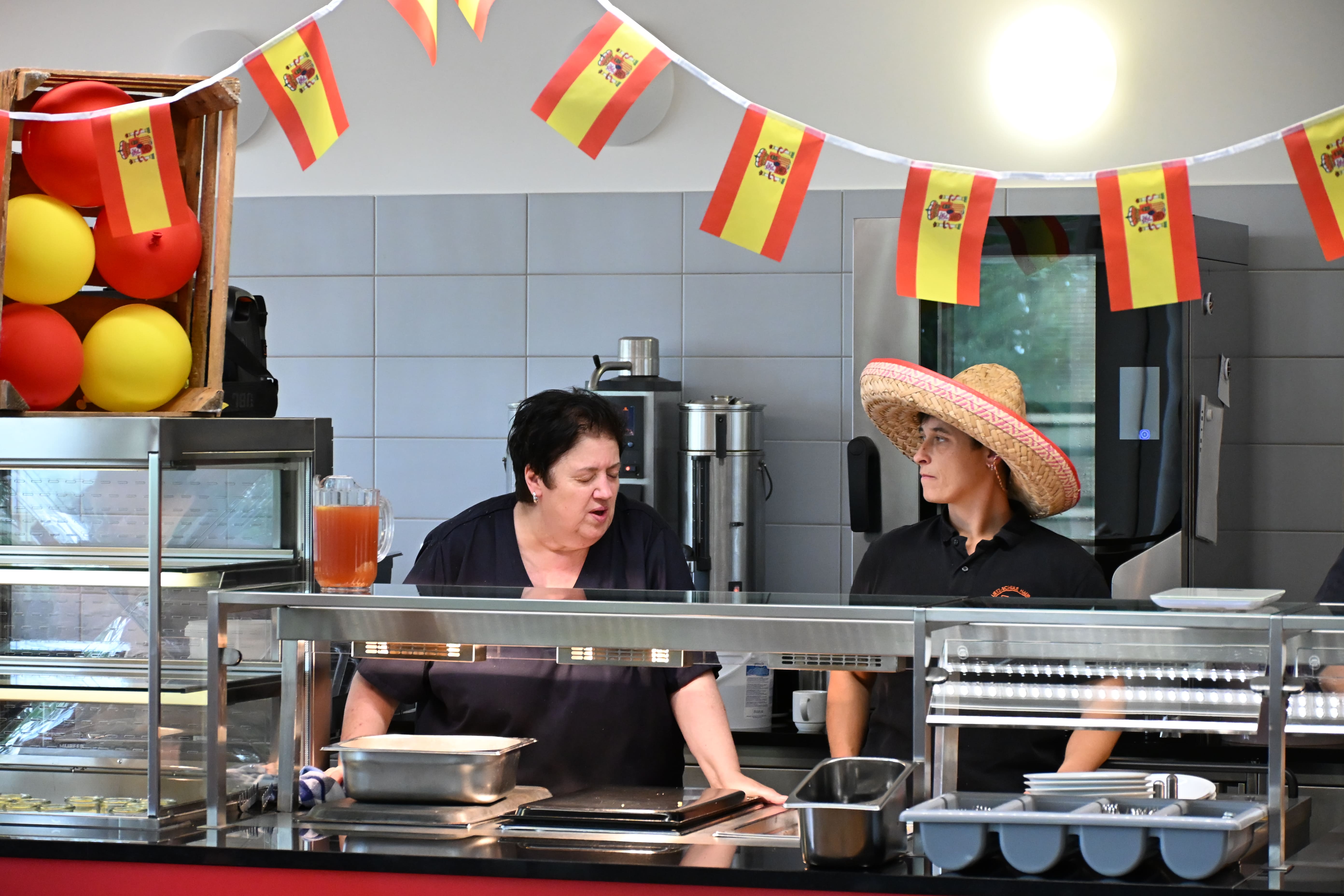 Zwei Frauen in dunkler Kleidung an einer Essenstheke mit spanischer Deko