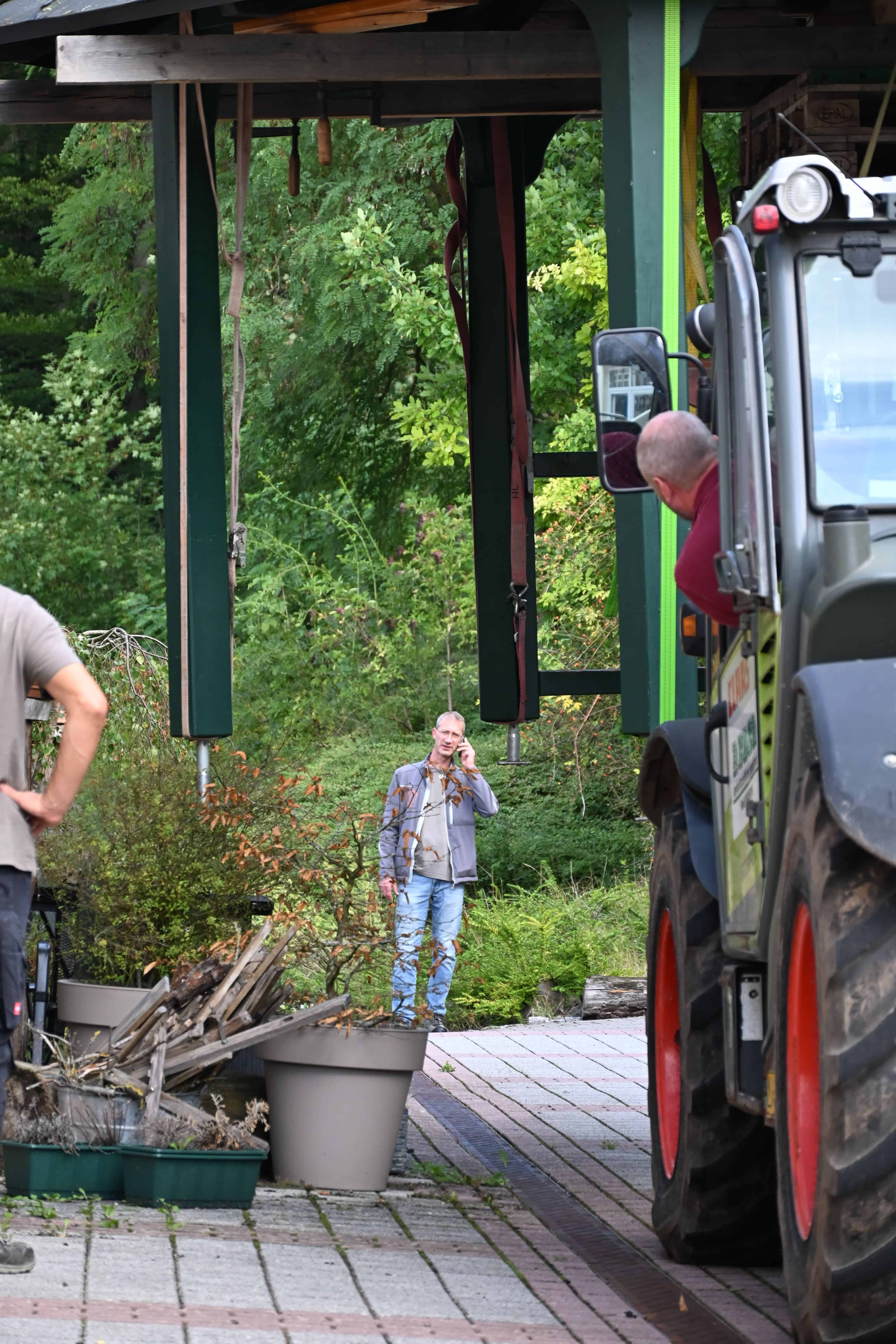 Ein Mann telefoniert konzentriert im Freien neben einem Traktor und Gruen