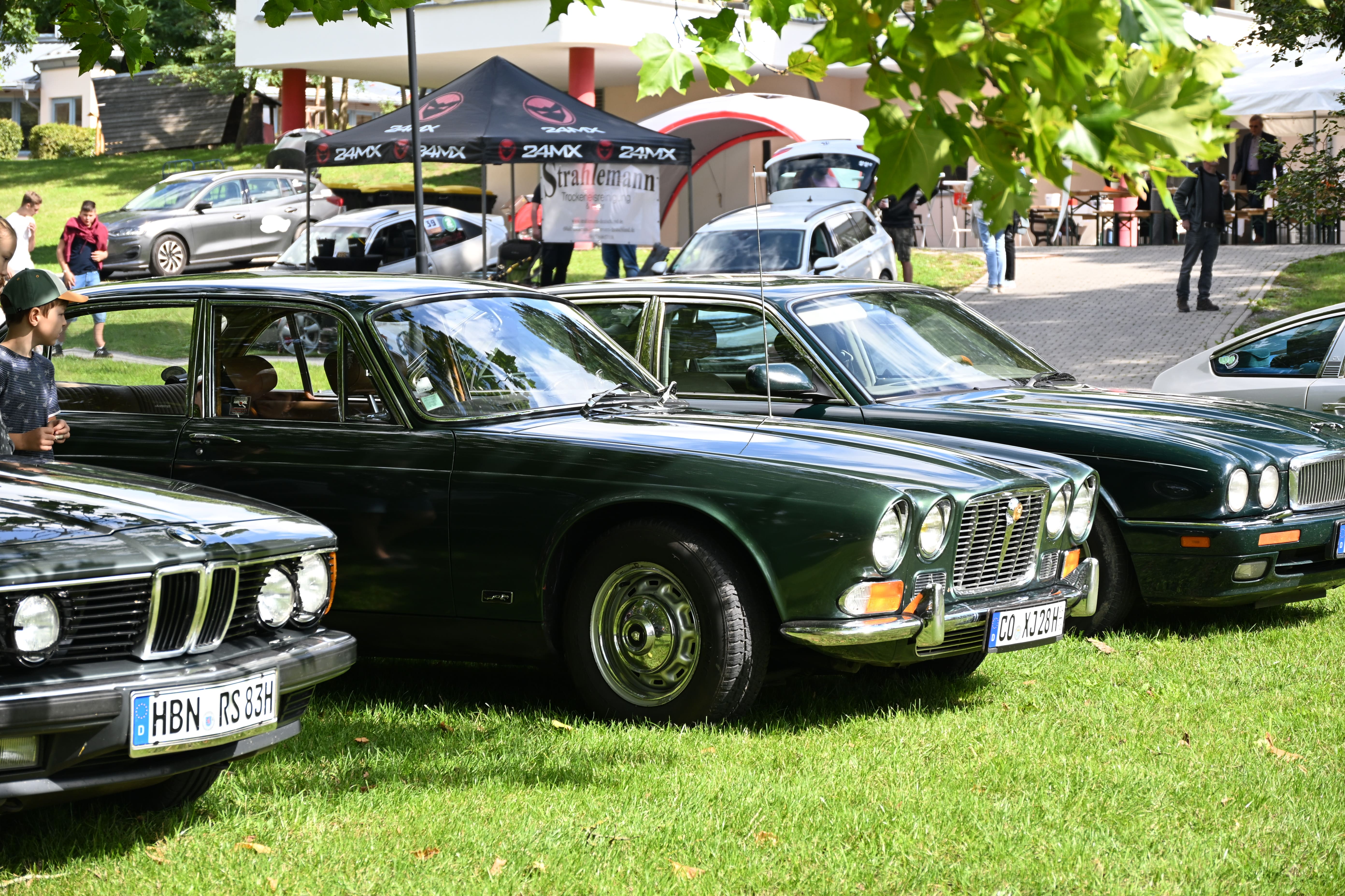 Dunkelgruene Oldtimer Fahrzeuge stehen bei einer Autoschau auf einer Wiese