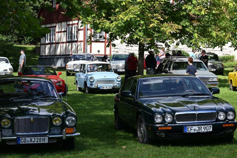 Oldtimertreffen mit Jaguar und Trabant auf einer Wiese vor Fachwerkhaus