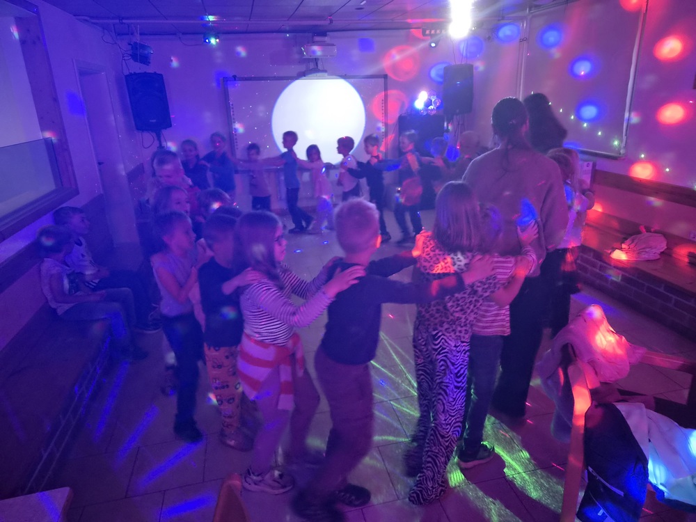 Froehlich tanzende Kinder bei einer Disco mit bunten Lichtern im Raum
