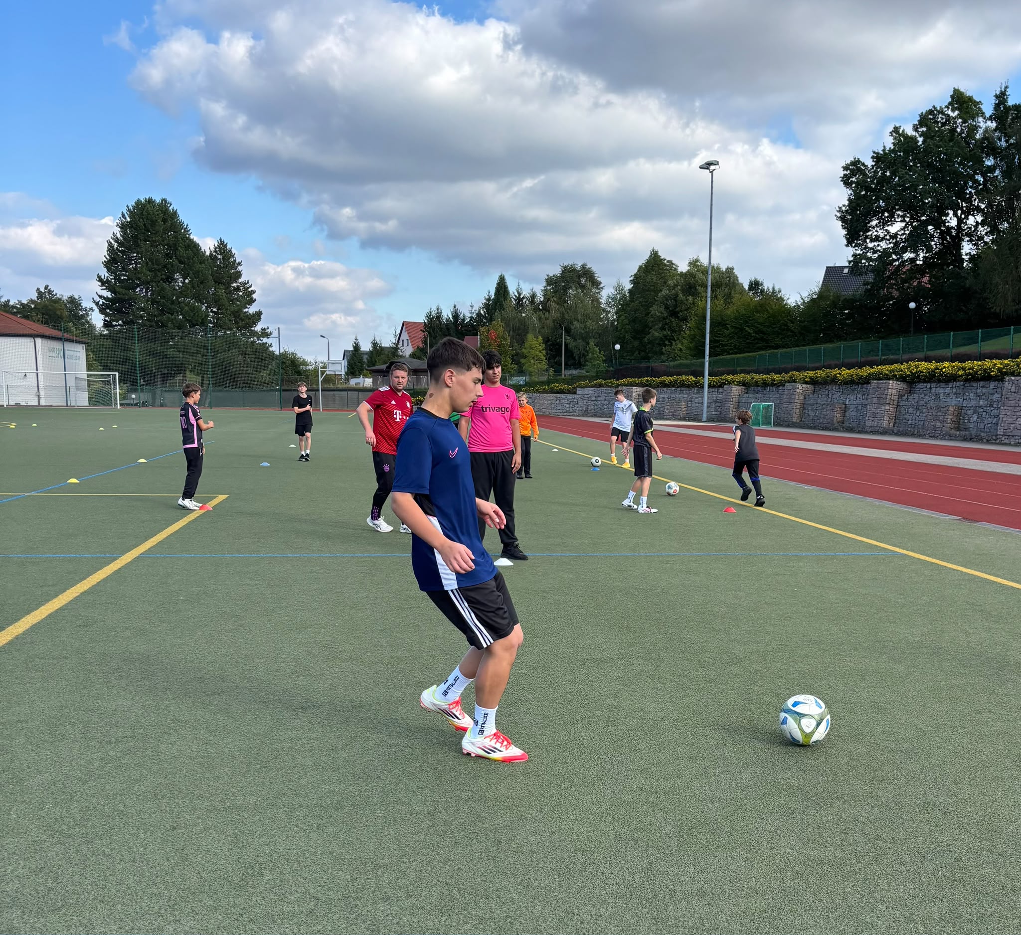 Ein konzentrierter Junge im blauen Trikot spielt beim Fussballtraining mit dem Ball