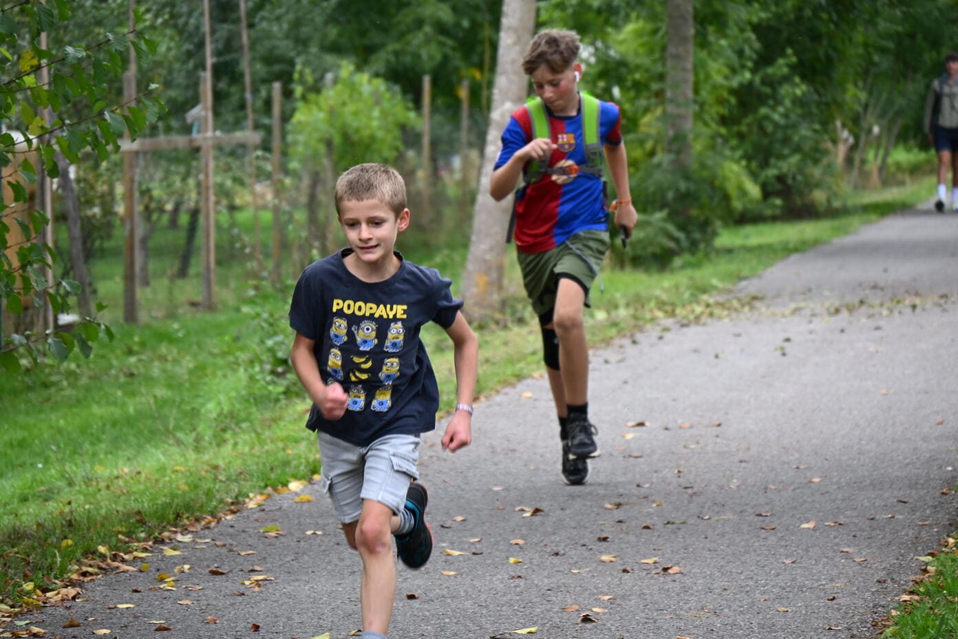 Zwei laechelnde Jungen laufen auf einem Weg durch gruene Natur