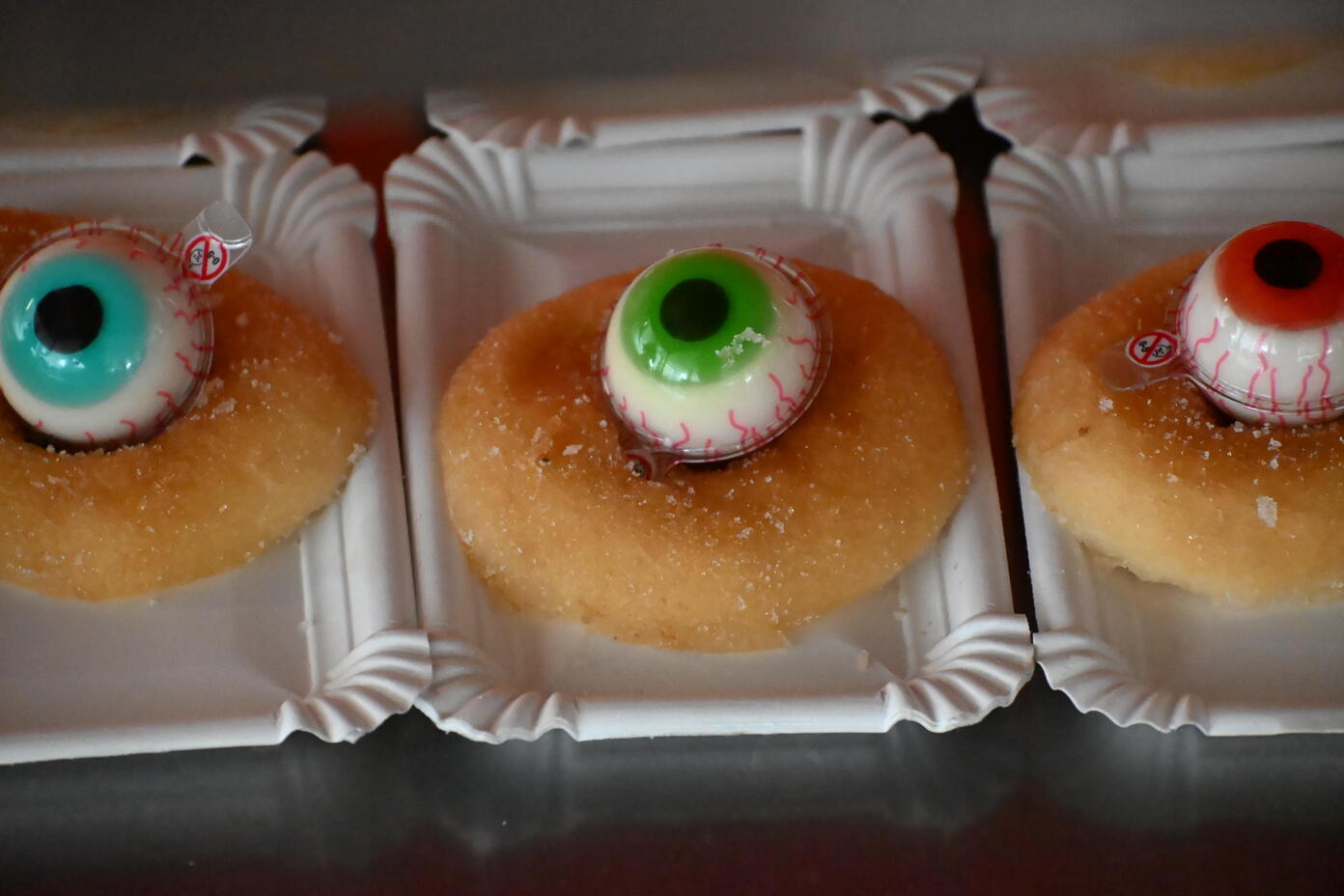 Drei Donuts mit blauen gruenen und roten Augen Dekorationen fuer Halloween