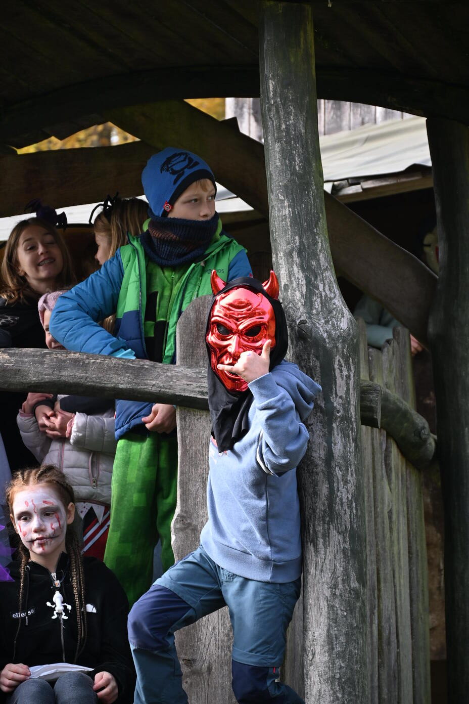 Ein Kind mit roter Teufelsmaske und blauem Pullover vor weiteren Kindern