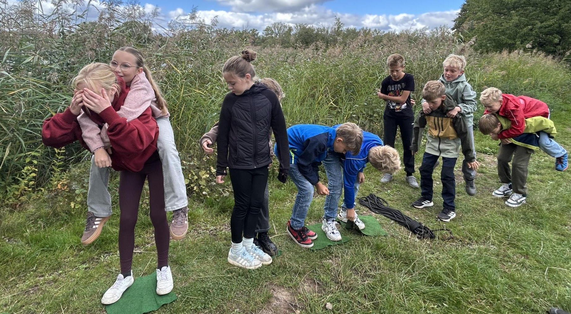 Kinder spielen fröhlich ein Teamspiel auf einer grünen Wiese im Freien